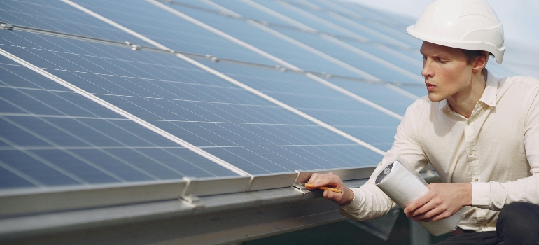 Solar technician in white shirt inspecting solar panels, and thinking about the rise of solar energy in Texas.